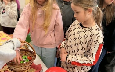 Na zdjęciu widzimy uczni&oacute;w na holu szkolnym podczas przerwy. Uczniowie biorą udział w quizie wiedzy na temat Włoch. Dookoła znajduje się dekoracja w kolorach włoskich, uczniowie biorą r&oacute;wnież udział w poczęstunku włoskim