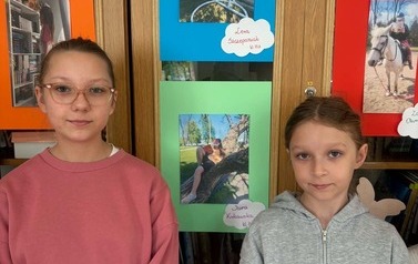 Uczniowie pozują do zdjęcia ze swoimi pracami fotograficznymi.