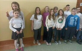 Na zdjęciu widzimy grupę uczni&oacute;w stojących na korytarzu szkolnym w strojach galowych . Dzieci czekają na rozpoczęcie konkursu. 