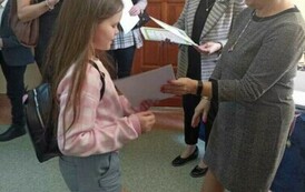 Na zdjęciu widzimy p. dyrektor MZEiA i dyrektor szkoły , Panie wręczają dyplom uczennicy. W tle stoją dwie dorosłe osoby.