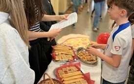 Na zdjęciu widzimy uczni&oacute;w na holu szkolnym podczas przerwy. Uczniowie biorą udział w quizie wiedzy na temat Włoch. Dookoła znajduje się dekoracja w kolorach włoskich, uczniowie biorą r&oacute;wnież udział w poczęstunku włoskim