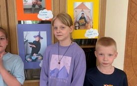 Uczniowie pozują do zdjęcia ze swoimi pracami fotograficznymi.