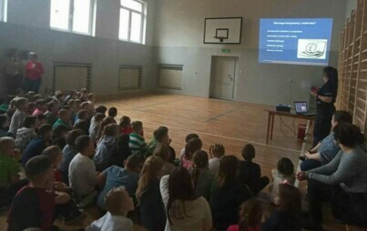 Uczniowie na sali gimnastycznej na spotkaniu z policjantem.
