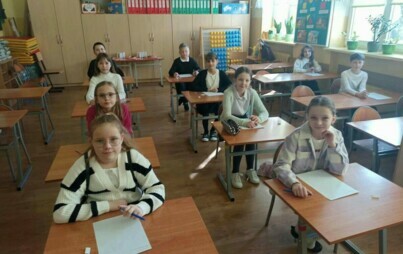 Na zdjęciu widzimy uczniów siedzących przy ławkach i czekających w skupieniu na rozpoczęcie konkursu Małe Dyktando.