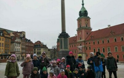 Na zdjęciu widzimy grupę uczniów za nimi Zamek Królewski w Warszawie i Kolumna Zygmunta.