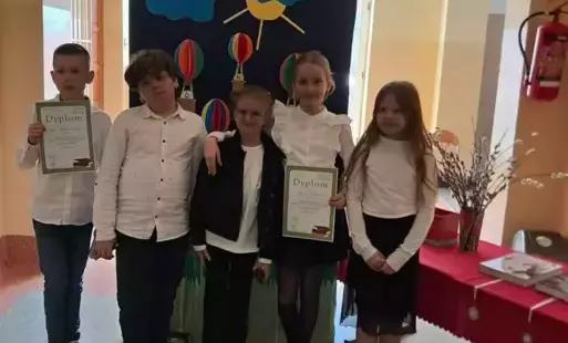 Na zdjęciu widzimy uczniów, którzy pozują do zdjęcia z otrzymanymi dyplomami w ręku nad nimi napis Małe Dyktando