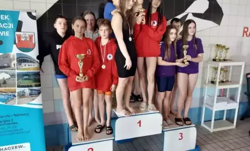 Na zdjęciu uczniowie stojący na podium z wygraną na lokalnej pływalni