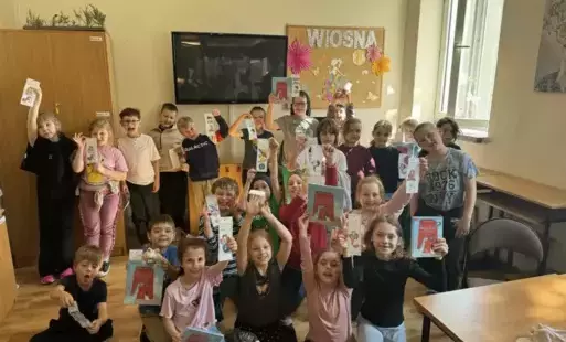 Na zdjęciu widzimy grupę uczniów w bibliotece szkolnej którzy prezentują swoje prace