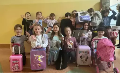 Na zdjęciu widzimy uczniów klasy II pozujących do zdjęcia z zamiennikami plecaków" w czym można przynieść książki do szkoły"