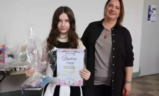 Na zdjęciu widzimy uczennicę , w ręku trzyma dyplom i nagrodę obok towarzyszy organizator konkursu.