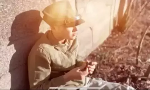 Na zdjęciu widzimy chłopca przebranego w mundur wojskowy, opiera się o ścianę