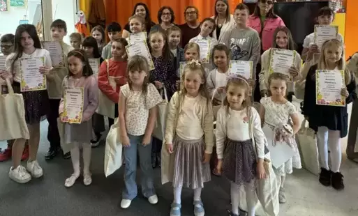 Na zdjęciu grupa dzieci w Bibliotece Publicznej pozuje do grupowego zdjęcia po rozdaniu nagród w konkursie ekologicznym