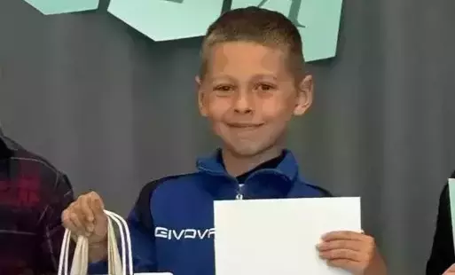 Na zdjęciu widzimy uśmiechniętego chłopca który w ręku trzyma dyplom i nagrodę.