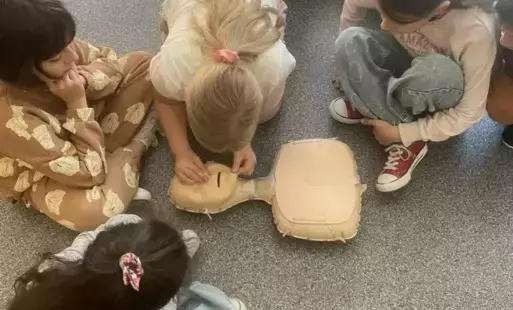 Na zdjęciu widzimy uczniów klas młodszych ćwiczących resuscytację na fantomie