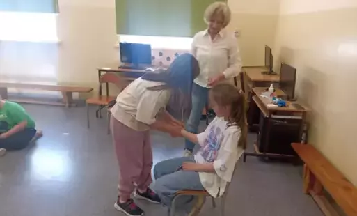 Na zdjęciu widzimy jak dwie uczennice klasy młodszej pod okiem pani pielęgniarki udzielają sobie pierwszej pomocy
