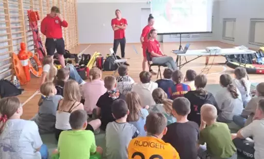 Na zdjęciu widzimy uczniów na sali gimnastycznej uczestniczących w zajęciach prowadzonych przez WOPR