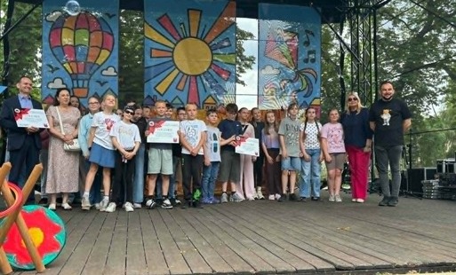 Na zdjęciu widzimy grupę szczęśliwych uczniów która stoi na scenie po odebraniu nagrody w konkursie Stop Przemocy Rówieśniczej.